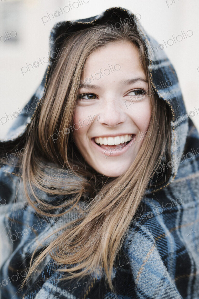 A young woman in a tartan plaid shawl outdoors in the winter.