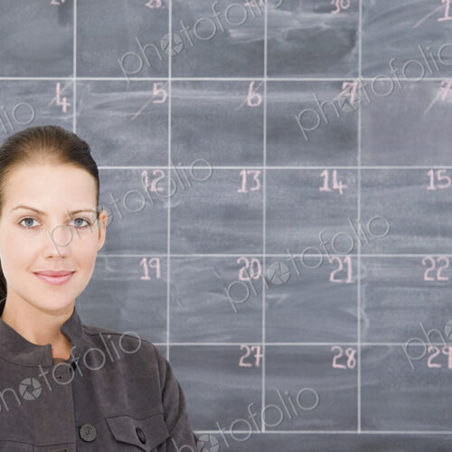 A young woman in front of a blackboard marked out as a calender.