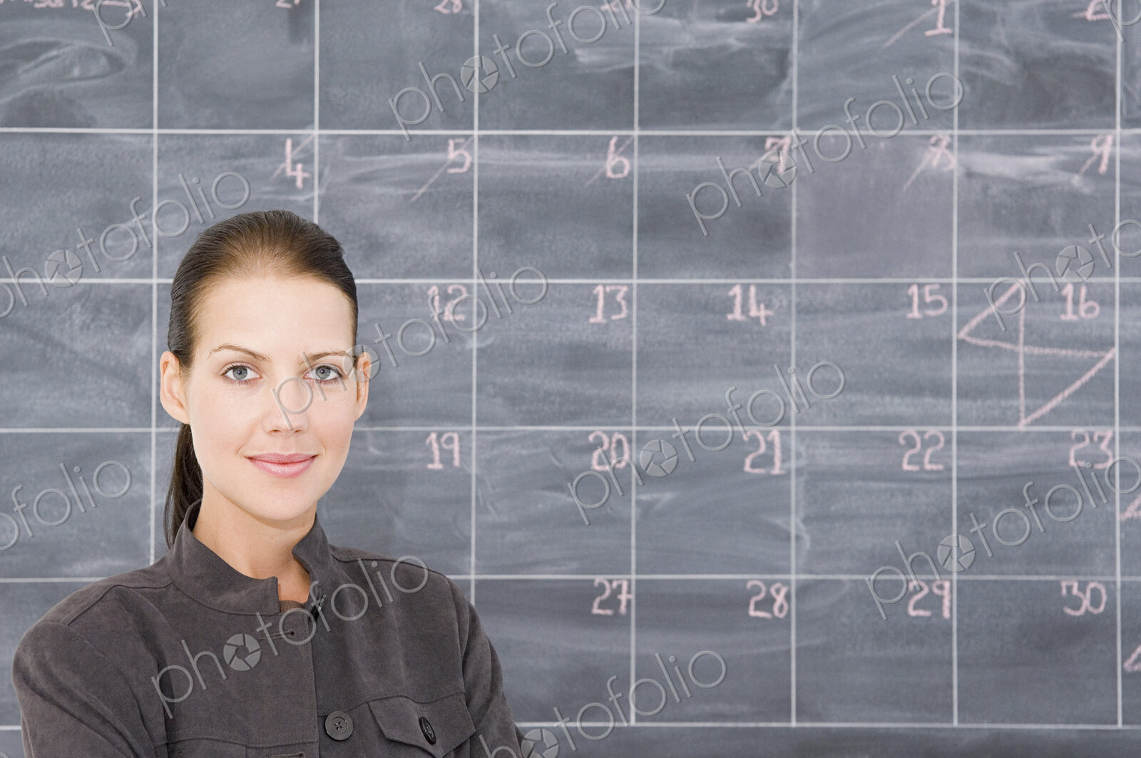 A young woman in front of a blackboard marked out as a calender.
