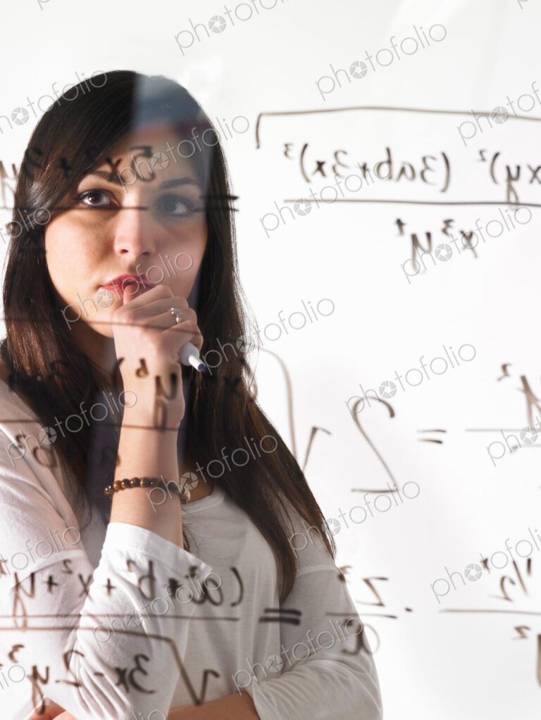 A young woman looking at a mathematical equation written out with black marker on a…