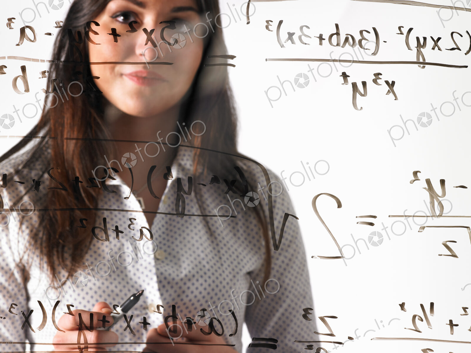 A young woman looking at a mathematical equation written out with black marker on a…