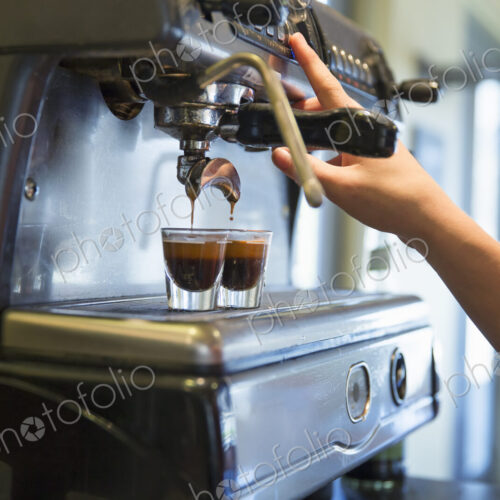 A young woman making coffee using a large coffee machine. A young woman making coffee using a large coffee machine.