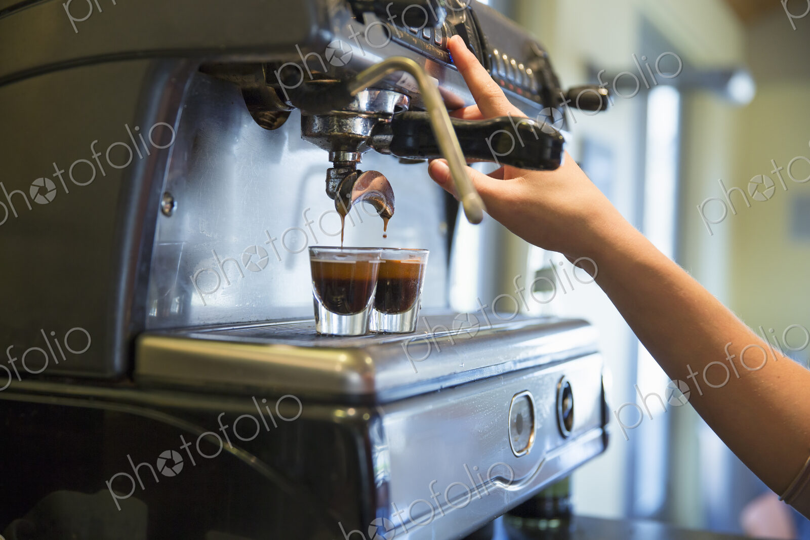 A young woman making coffee using a large coffee machine.