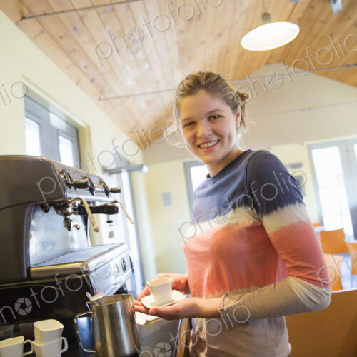 A young woman making coffee using a large coffee machine. A young woman making coffee using a large coffee machine.