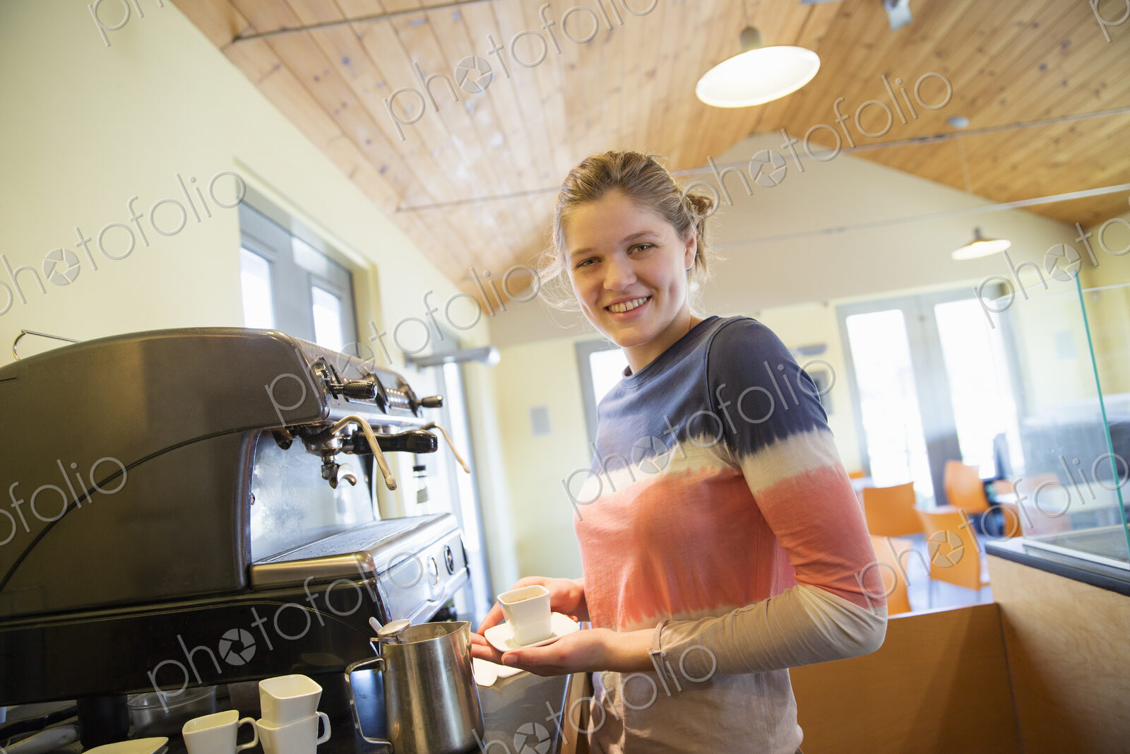 A young woman making coffee using a large coffee machine.