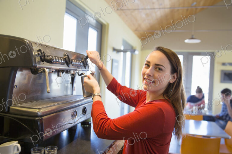 A young woman making coffee using a large coffee machine.