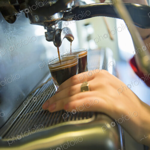 A young woman making coffee using a large coffee machine. A young woman making coffee using a large coffee machine.