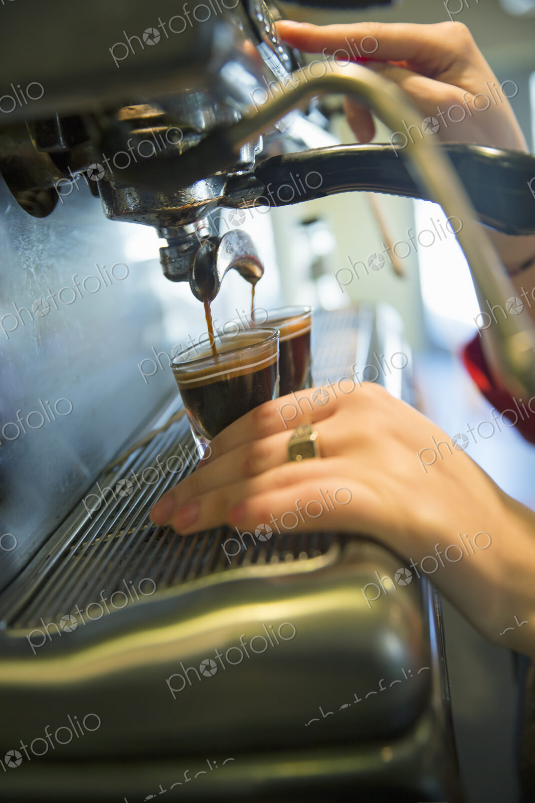 A young woman making coffee using a large coffee machine.