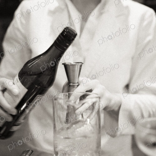A young woman mixing a cocktail, a mixologist at work.