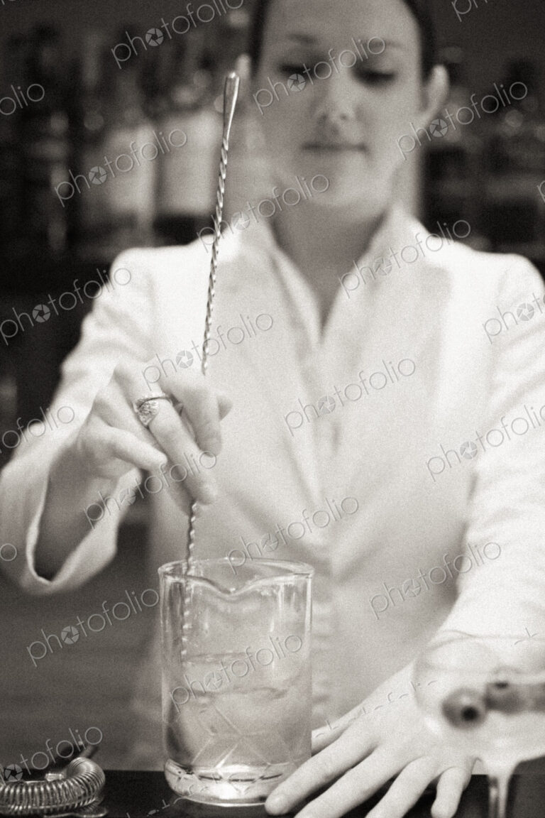 A young woman mixing a cocktail, a mixologist at work.