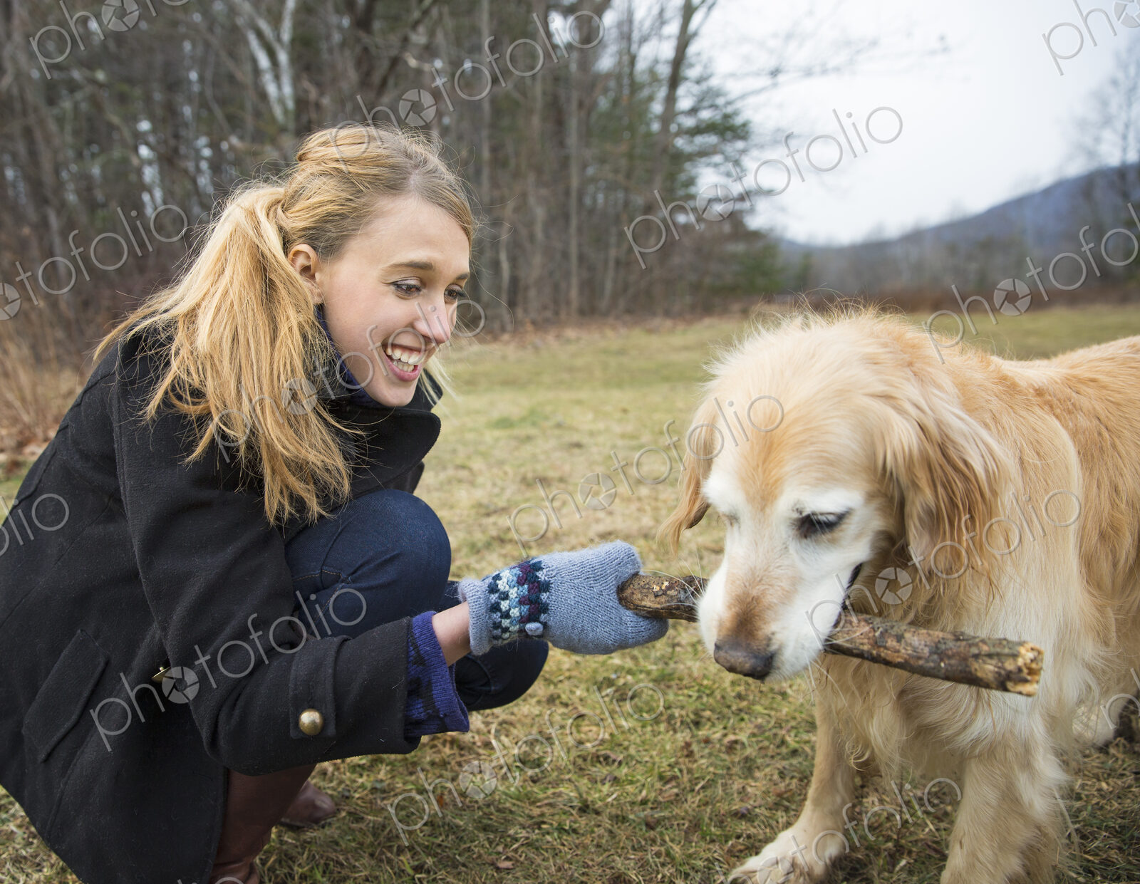 A young woman outdoors in the winter, on a walk with a golden retriever dog.