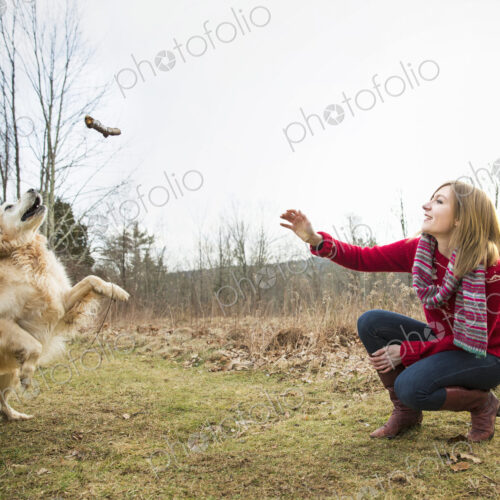 A young woman outdoors in the winter, on a walk with a golden retriever dog. A young woman outdoors in the winter, on a walk with a golden retriever dog.