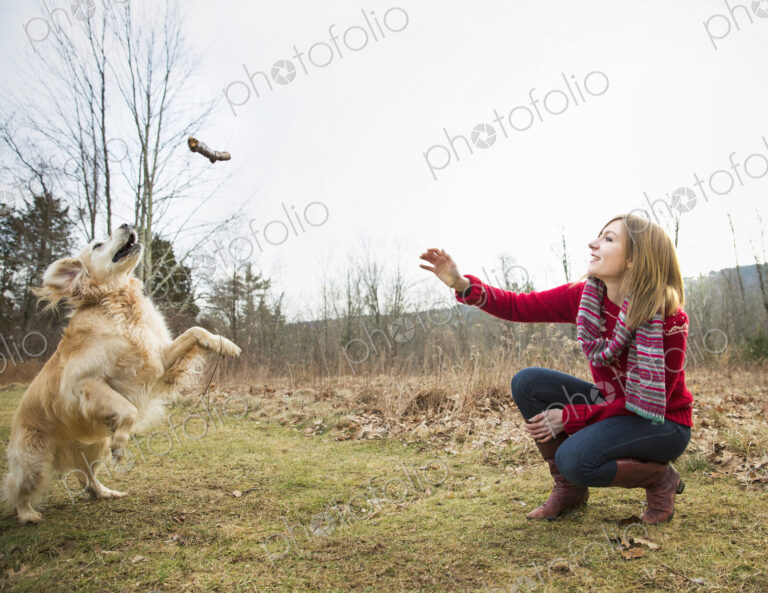 A young woman outdoors in the winter, on a walk with a golden retriever dog.