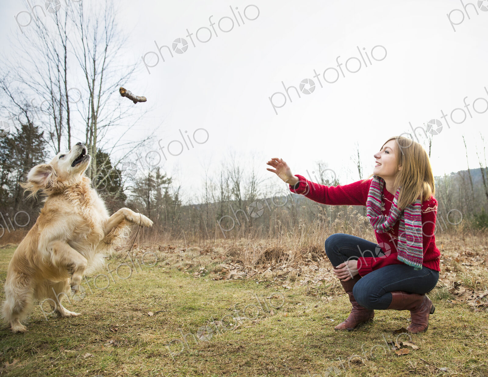 A young woman outdoors in the winter, on a walk with a golden retriever dog.