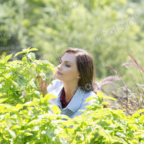 A young woman outdoors surrounded by plants.