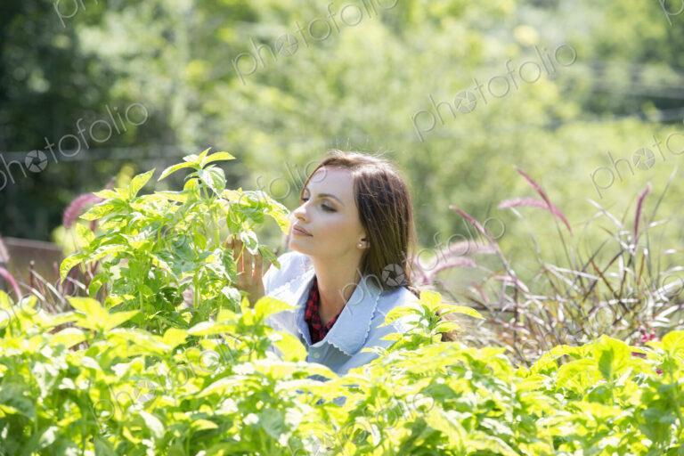 A young woman outdoors surrounded by plants.