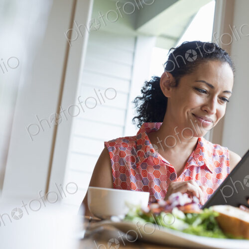 A young woman reading from the screen of a digital tablet, seated at a table. Coffee… A young woman reading from the screen of a digital tablet, seated at a table. Coffee…