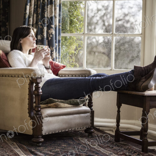 A young woman relaxing at home, with her feet up, having a cup of tea. A young woman relaxing at home, with her feet up, having a cup of tea.