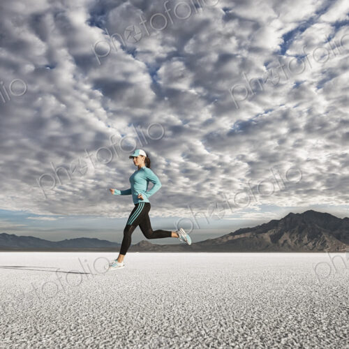 A young woman running through the landscape on the salt flats surface near Salt Lake city.