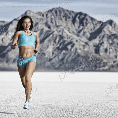 A young woman running through the landscape on the salt flats surface near Salt Lake city.