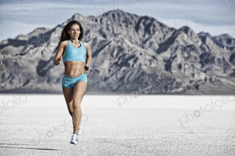 A young woman running through the landscape on the salt flats surface near Salt Lake city.