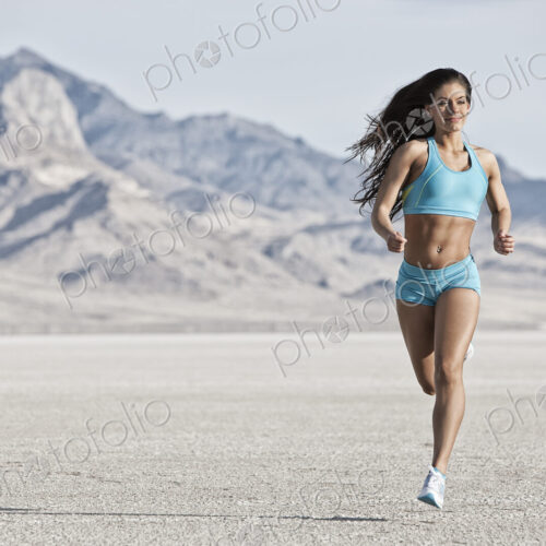 A young woman running through the landscape on the salt flats surface near Salt Lake city.