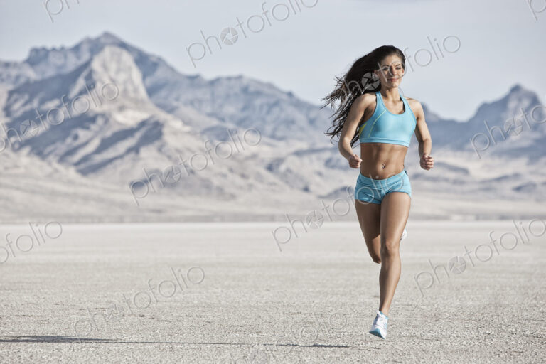 A young woman running through the landscape on the salt flats surface near Salt Lake city.