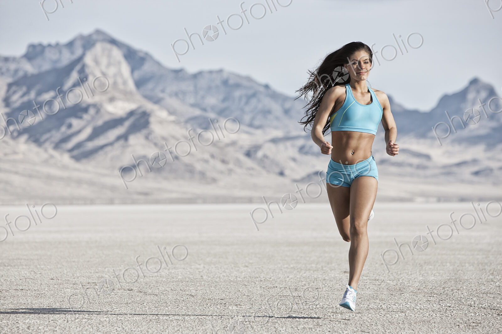 A young woman running through the landscape on the salt flats surface near Salt Lake city.