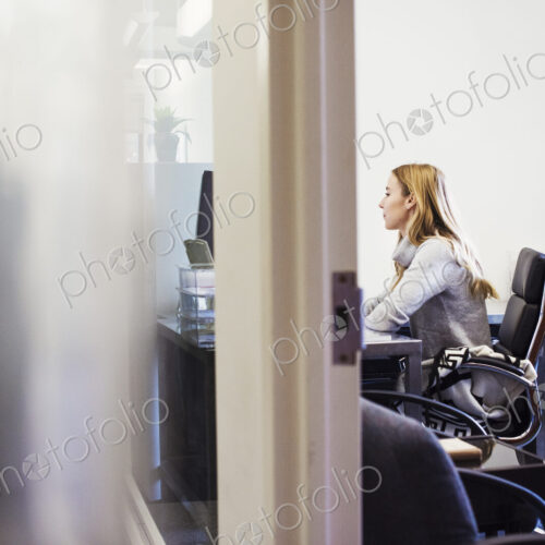 A young woman sitting at a desk in an office. A young woman sitting at a desk in an office.