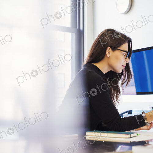A young woman sitting at a desk in an office looking at paperwork. A young woman sitting at a desk in an office looking at paperwork.