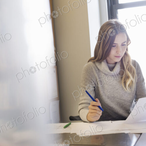 A young woman sitting at a desk in an office looking at paperwork. A young woman sitting at a desk in an office looking at paperwork.