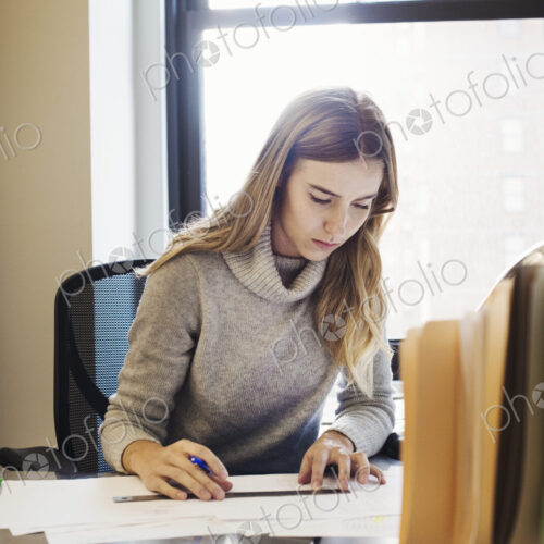 A young woman sitting at a desk in an office typing. A young woman sitting at a desk in an office typing.