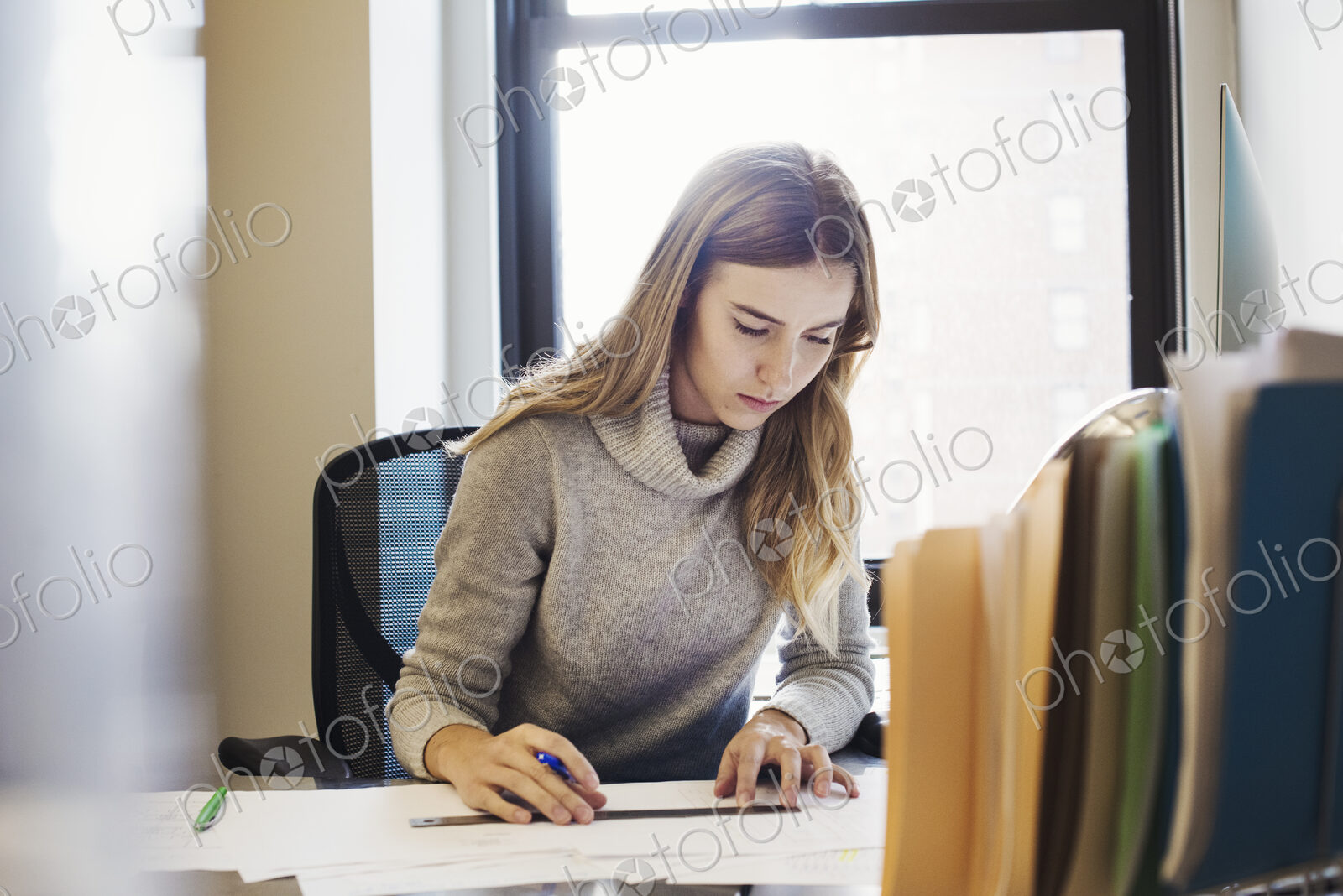 A young woman sitting at a desk in an office typing.