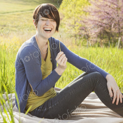 A young woman sitting in an open space, a grass field, on a blanket. A young woman sitting in an open space, a grass field, on a blanket.
