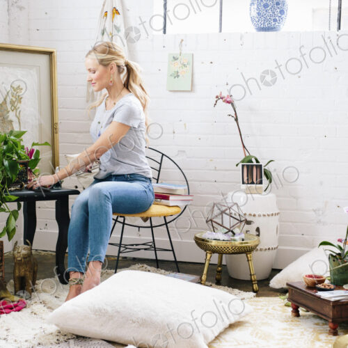 A young woman sitting on a chair in an apartment decorated with pictures and plants. A young woman sitting on a chair in an apartment decorated with pictures and plants.