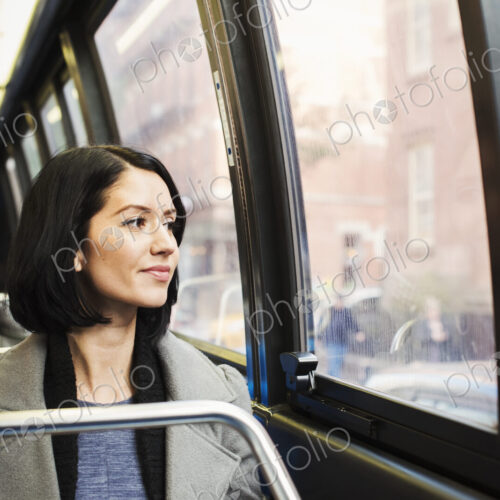 A young woman sitting on a train looking out of the window at an urban landscape, with… A young woman sitting on a train looking out of the window at an urban landscape, with…