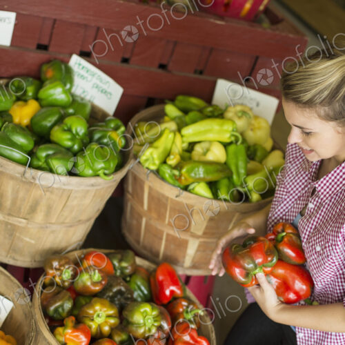 A young woman sorting different types of bell pepper for sale. A young woman sorting different types of bell pepper for sale.