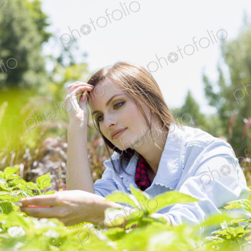 A young woman standing by racks of plants, in a commercial nursery. A young woman standing by racks of plants, in a commercial nursery.
