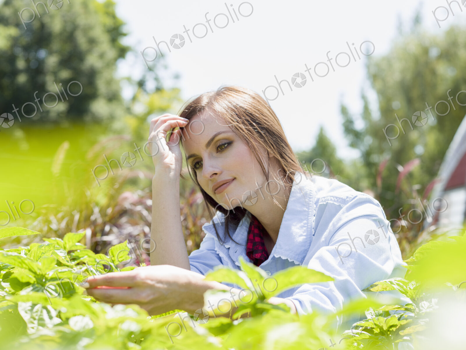 A young woman standing by racks of plants, in a commercial nursery.