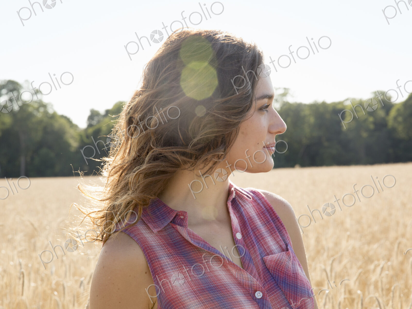 A young woman standing in a field of tall ripe corn.