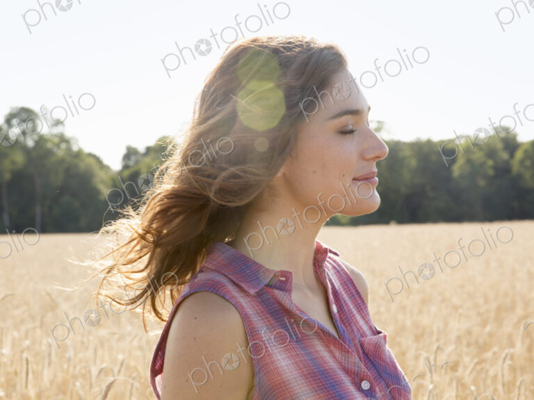 A young woman standing in a field of tall ripe corn.