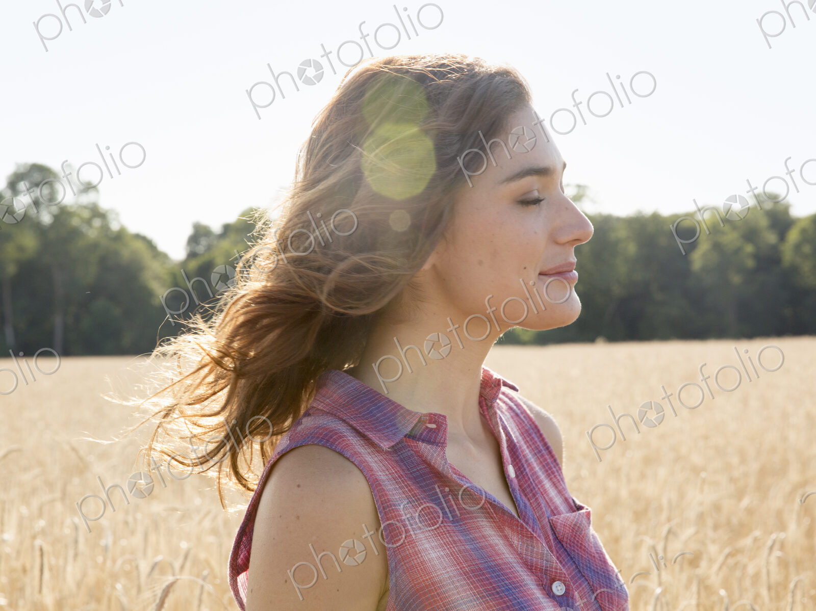 A young woman standing in a field of tall ripe corn.