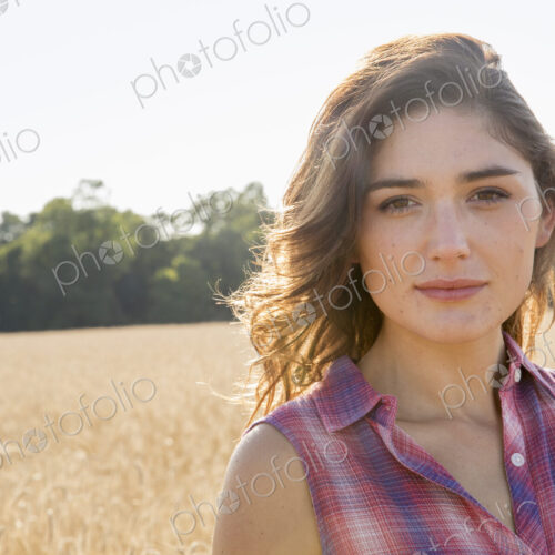 A young woman standing in a field of tall ripe corn. A young woman standing in a field of tall ripe corn.