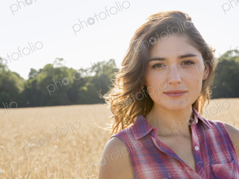 A young woman standing in a field of tall ripe corn.