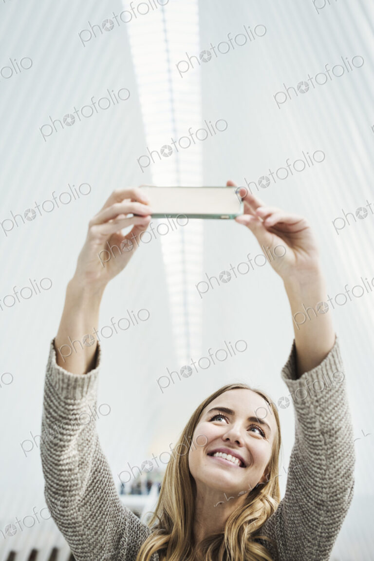 A young woman taking a photograph with her phone, a selfy in the World Trade Centre…