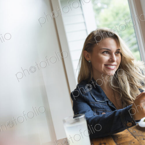 A young woman using a smart phone, seated at a table. Coffee and a sandwich. A young woman using a smart phone, seated at a table. Coffee and a sandwich.