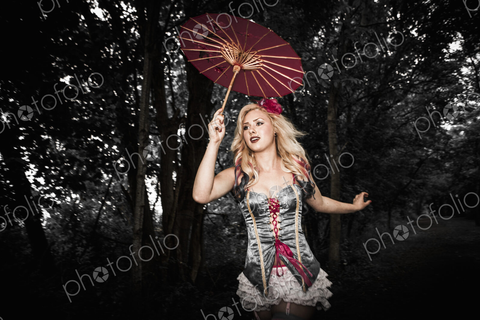 A young woman wearing a laced basque and frilly bloomers, striped stockings and…
