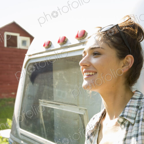 A young woman wearing sunglasses by a silver coloured trailer.
