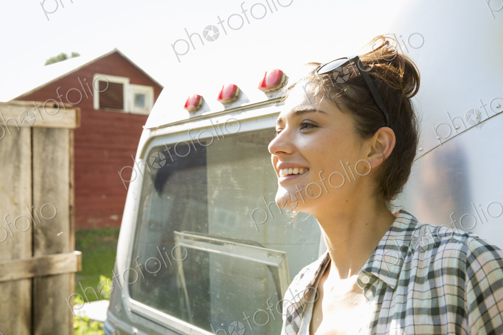 A young woman wearing sunglasses by a silver coloured trailer.