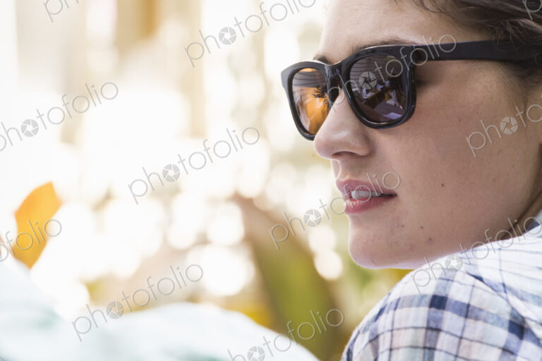 A young woman wearing sunglasses turning towards a man.